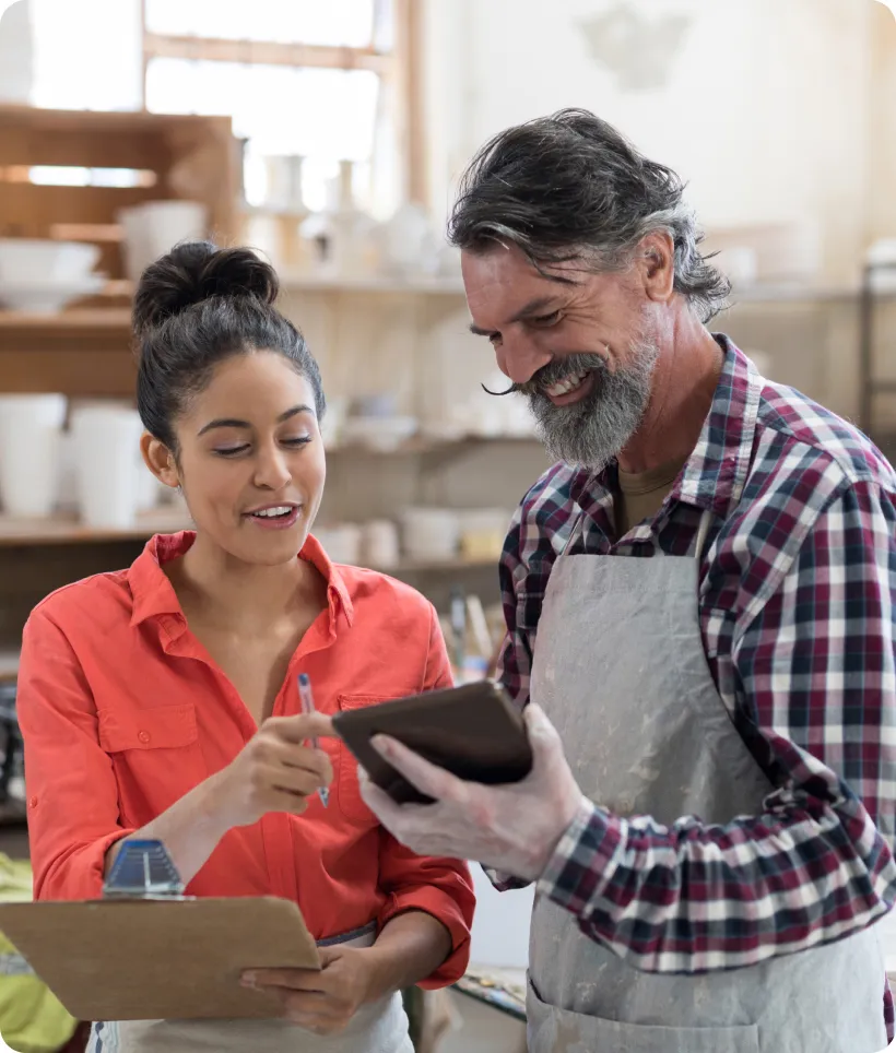 A business owner and a colleague reviewing figures on a tablet in their shop