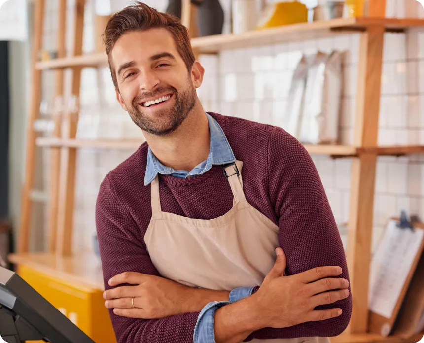 A smiling café owner standing behind his counter